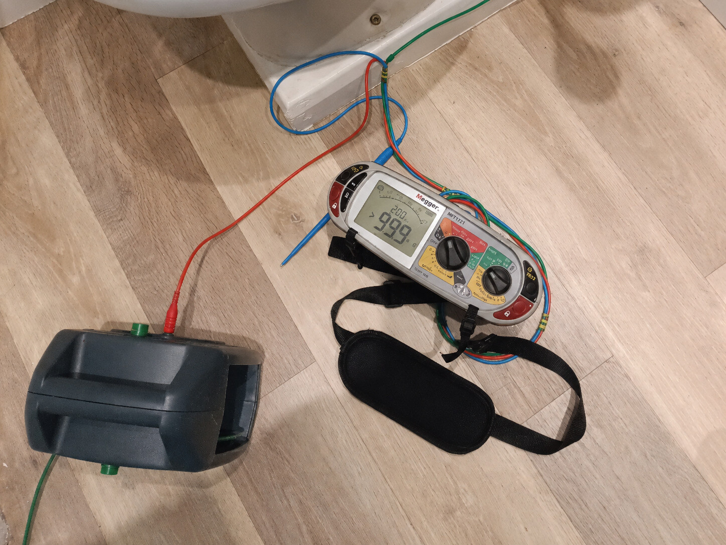 Multifunction electrical tester and test leads in use during inspection of a domestic bathroom circuit