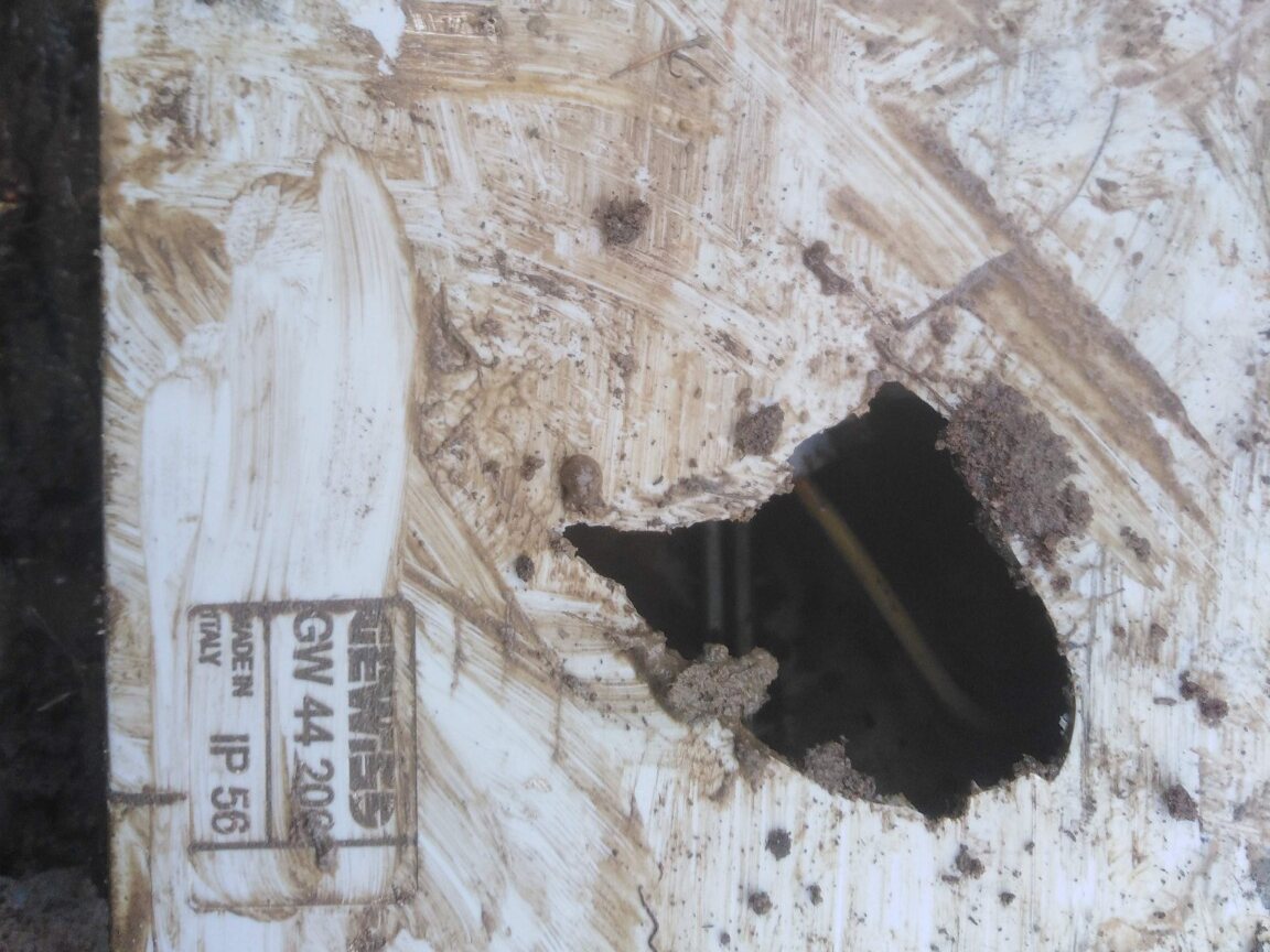 Damaged lid from a buried electrical enclosure showing an IP56 marking and a large opening