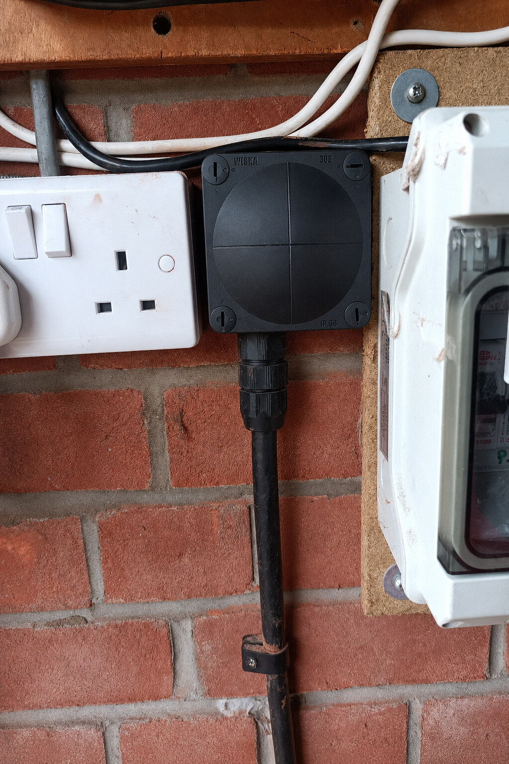 Closed black Wiska junction box with an armoured cable secured at the lower cable entry after remedial work